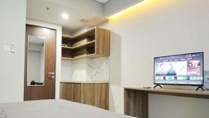A modern bedroom with a bed, a TV mounted on a wooden console, and a built-in wardrobe with a mirror.