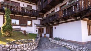 Una cabaña tradicional con paredes de piedra, balcones de madera y un camino de piedra que lleva a la entrada.