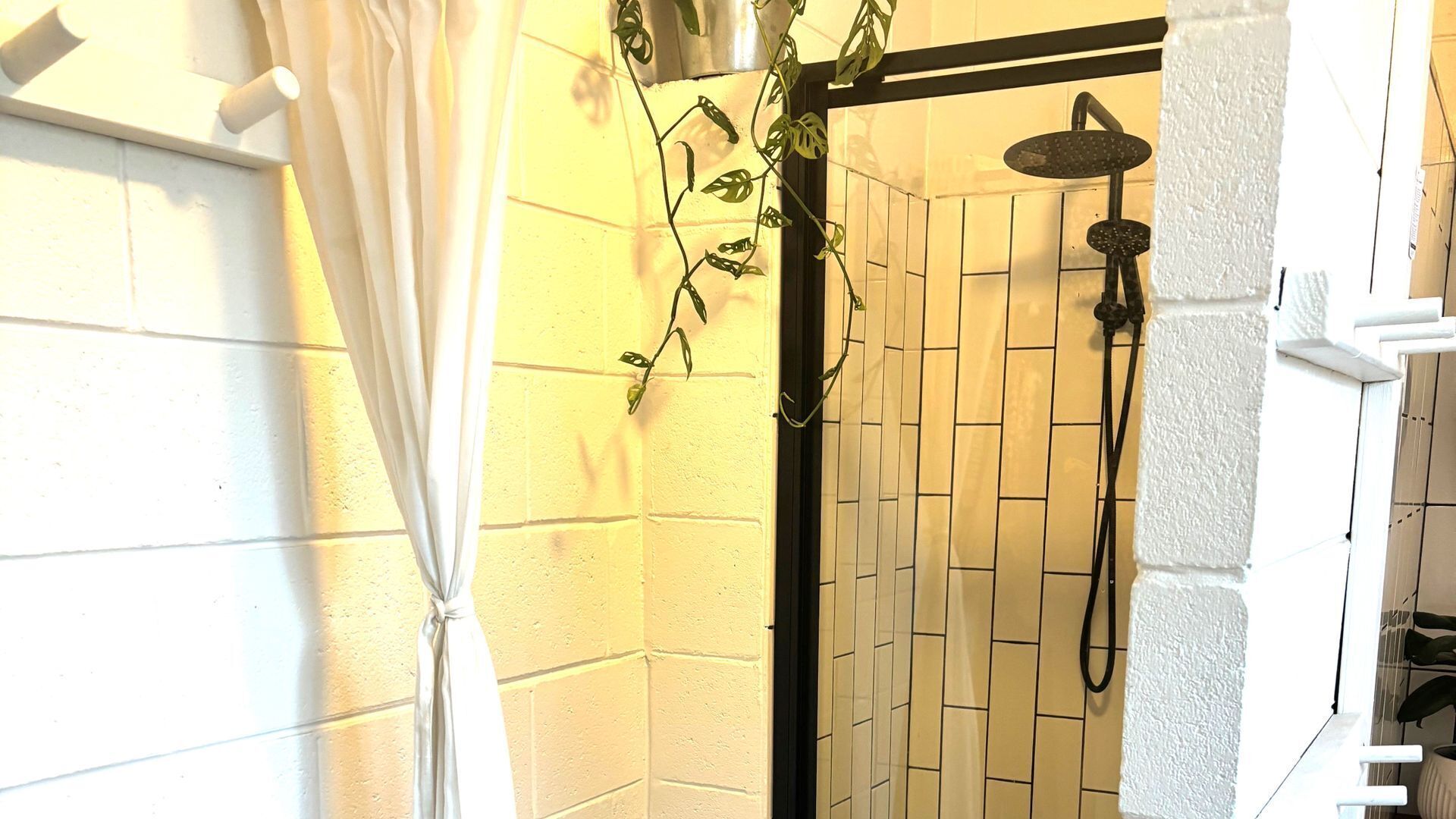 A shower area with a tiled wall, a showerhead, and a curtain.