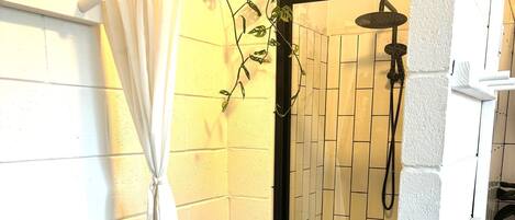 A shower area with a tiled wall, a showerhead, and a curtain.