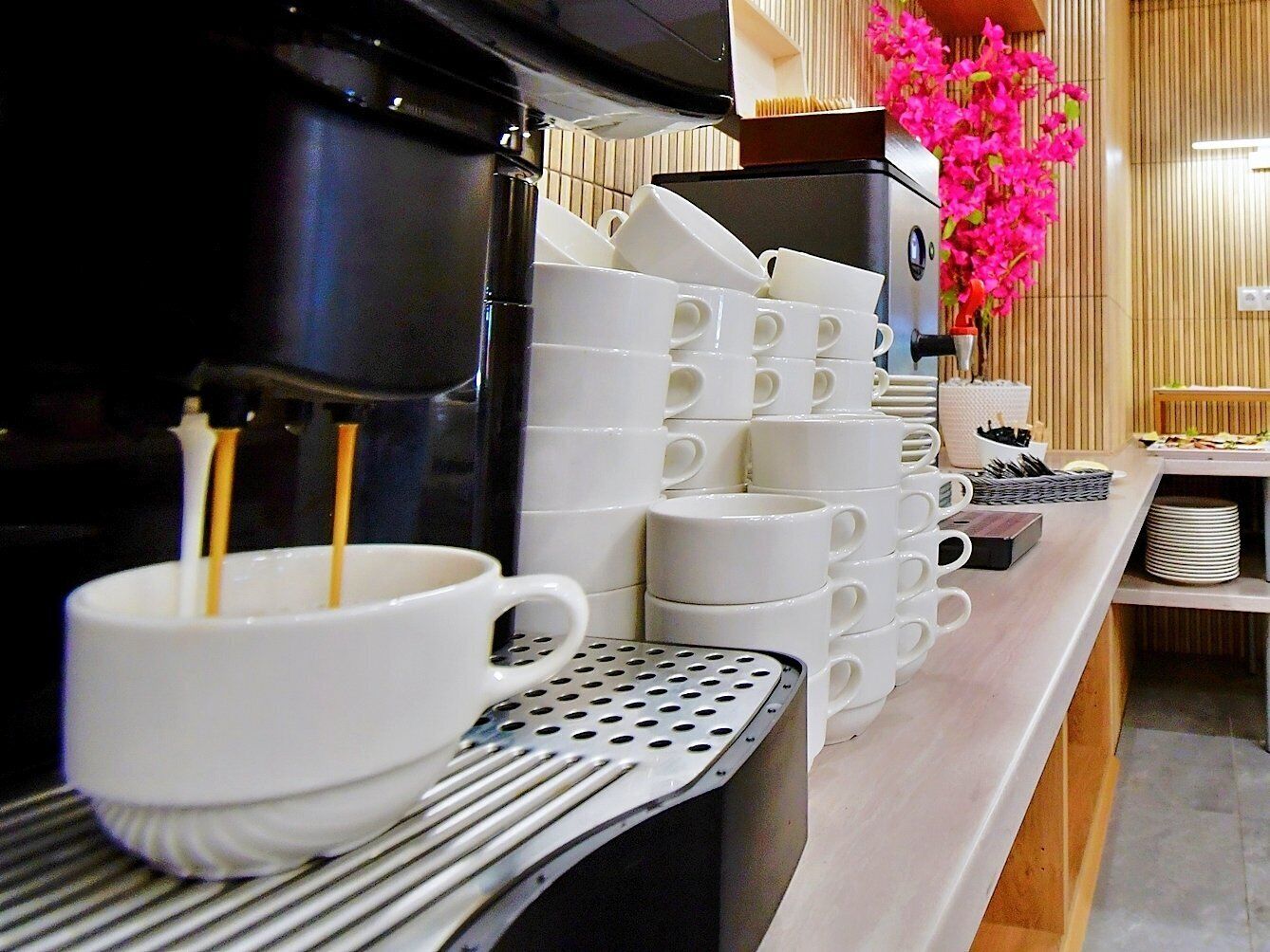 A coffee station with a coffee machine, stacked white cups, and a tray.
