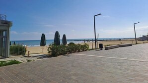 A paved walkway leading to a beach with a clear sky.