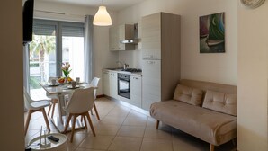A modern kitchen with a dining area, a sofa, and a painting on the wall.