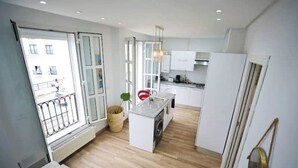 A modern kitchen with a central island, a dining area with a table and chairs, and a large window with a view of the outside. - Luxurious apartment with sea view in La Marsa (Marsa)