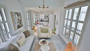 A spacious living room with a sofa, coffee table, and a decorative lamp. A kitchen is visible in the background. - Luxurious apartment with sea view in La Marsa (Marsa)