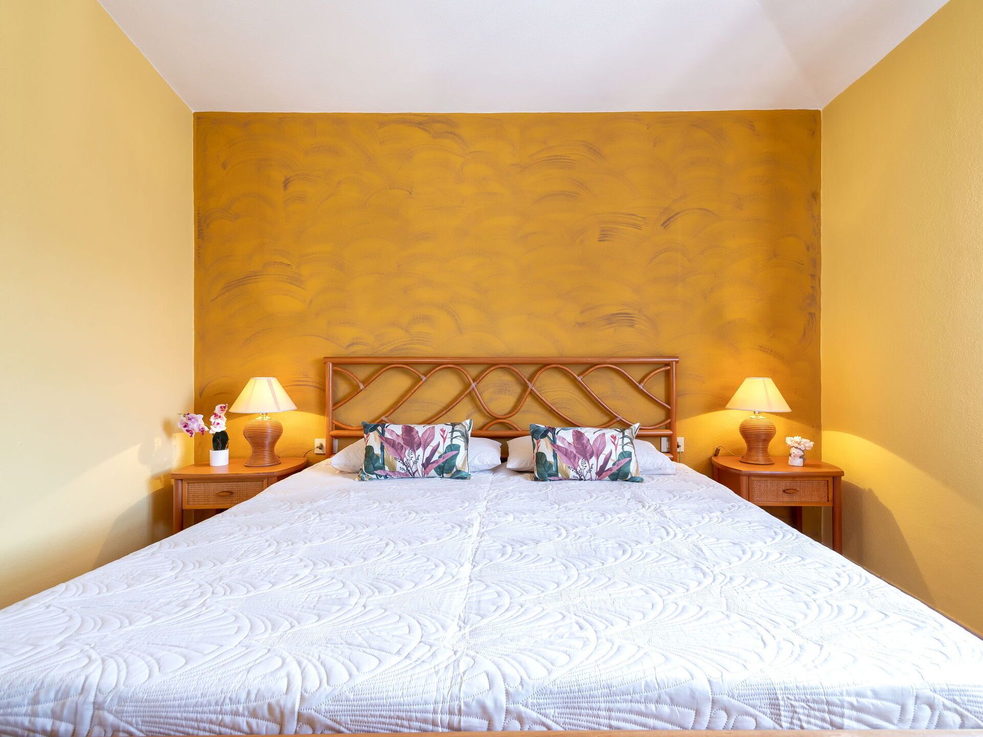 A hotel room with a large bed, two bedside tables with lamps, and a patterned wall.