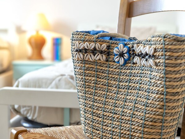 A wicker chair with a woven seat and backrest, and a matching woven bag with decorative elements.