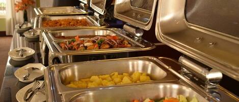 Disposición de un bufé con diversas opciones de comida, incluyendo ensaladas, papas y platos combinados.