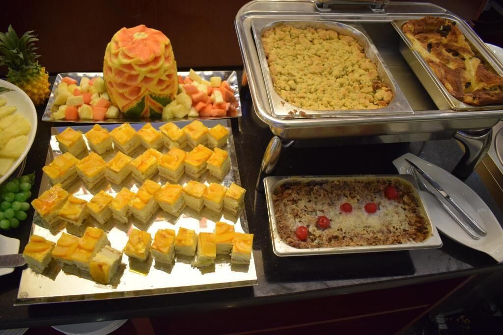 A buffet with various dishes including a carved watermelon, fruit salad, and several trays of food.