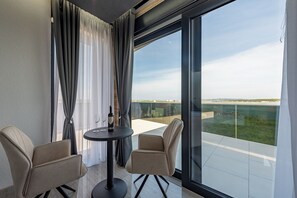 A modern balcony with two chairs, a table, and a bottle of wine. - Resort Travera (Privlaka)