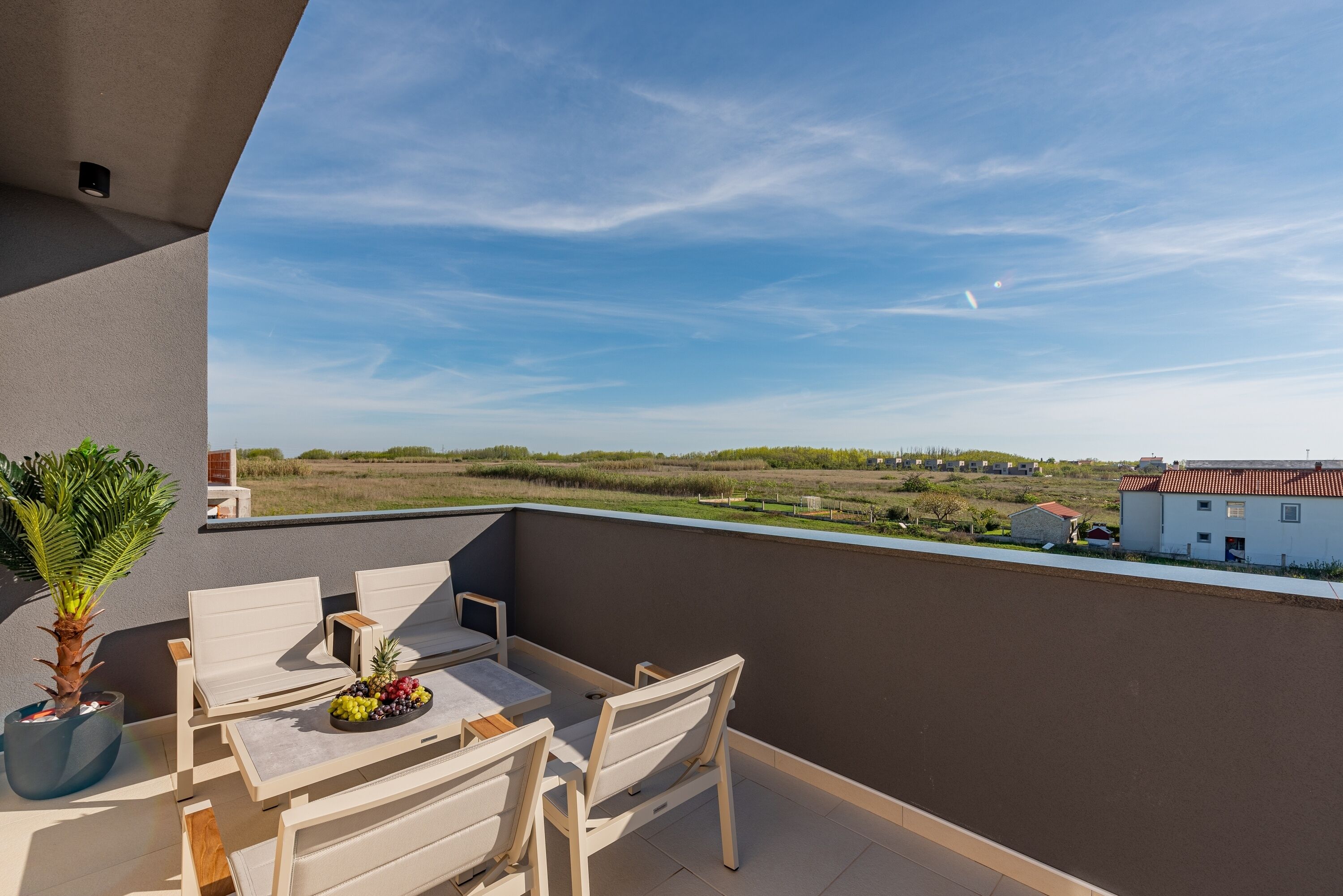 Un balcon avec une table, des chaises et un pot de fleurs.