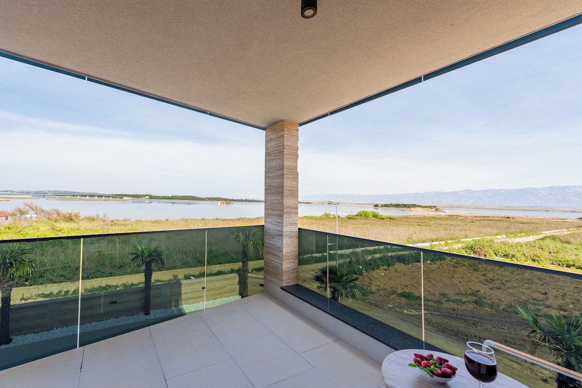 A balcony with a view of a lake and distant mountains.