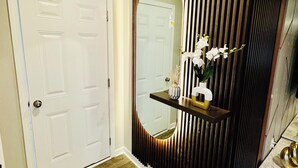 A hallway with a white door, a mirror, and a wooden panel wall. - Comfort house weekly discount and monthly discount (Cullman)