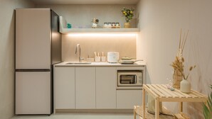 A compact kitchen with a refrigerator, sink, and built-in oven. - Busan Ji Villard Pension (Busan)