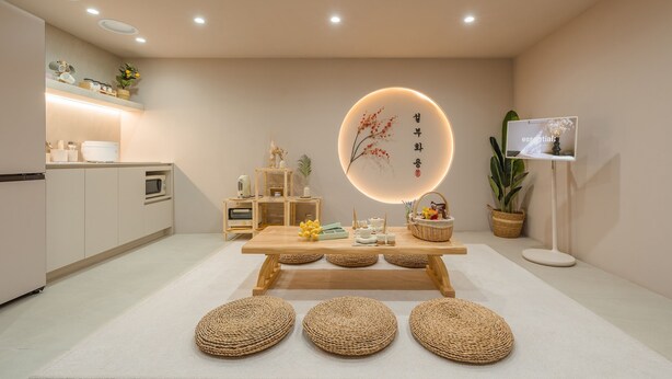 A modern kitchen with a wooden table, woven poufs, and a decorative wall piece. - Busan Ji Villard Pension (Busan)