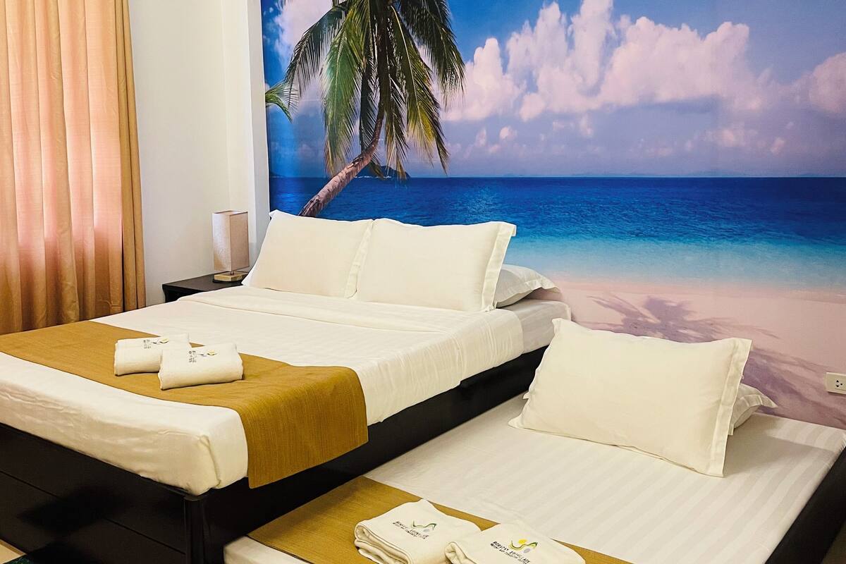 A hotel room with two beds, a large beach mural on the wall, and a checkered floor.