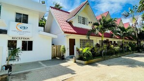 A hotel with a reception area, a red-tiled roof, and tropical landscaping. - Castle Rock Boracay (Boracay Island)