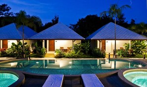 A resort with a swimming pool, lounge chairs, and a covered outdoor area with plants. - BAANCHONGFA RESORT (Takua Pa)