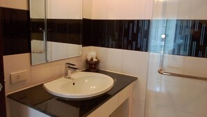 Un bagno con lavandino bianco, piano di lavoro nero e box doccia in vetro.