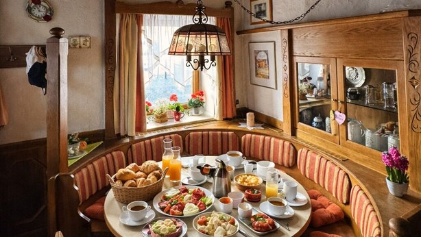 Una mesa redonda para comer con diversas opciones de desayuno, rodeada de sillas acolchadas.