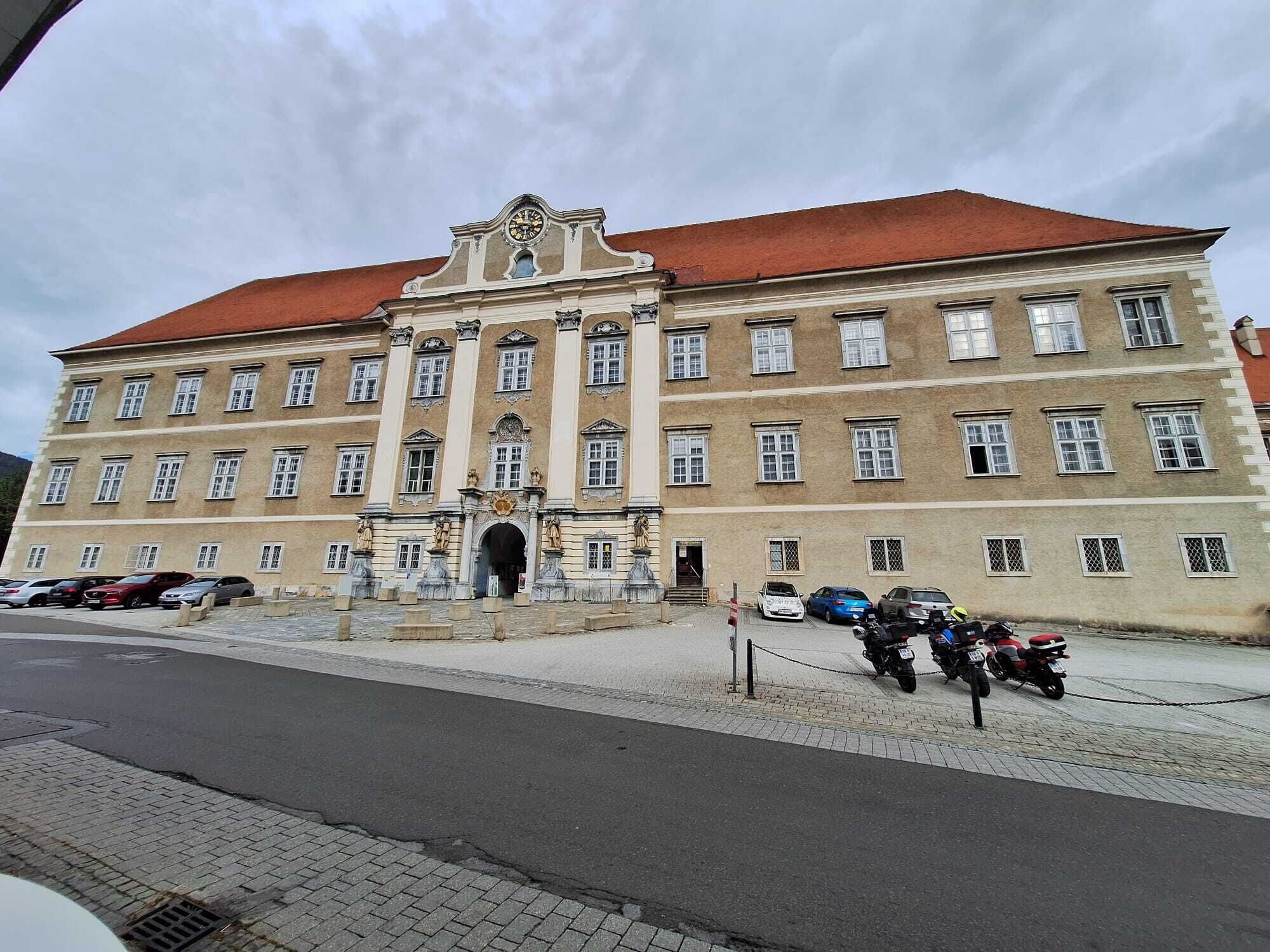 A large, historic building with a red roof and multiple windows.