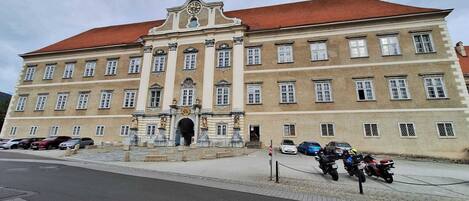 A large, historic building with a red roof and multiple windows.