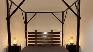A wooden four-poster bed with a headboard, two bedside tables, and a hanging light fixture.