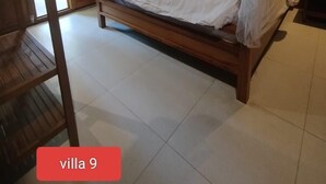 A bedroom with a wooden bed, white bedding, and a canopy. - Villa Lova Sambirenteng (Tejakula)