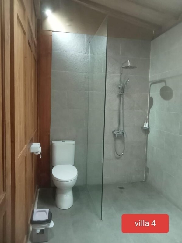 A compact bathroom with a toilet, a shower enclosure, and a weighing scale. - Villa Lova Sambirenteng (Tejakula)