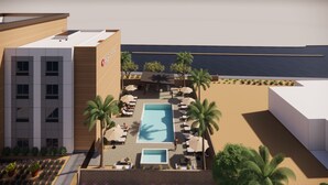 Un espace piscine sur le toit, avec des chaises longues et des parasols, une piscine et une vue sur l’océan.