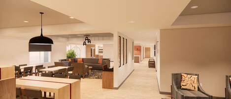 A spacious hotel lobby with a dining area, seating, and a hallway leading to other rooms.