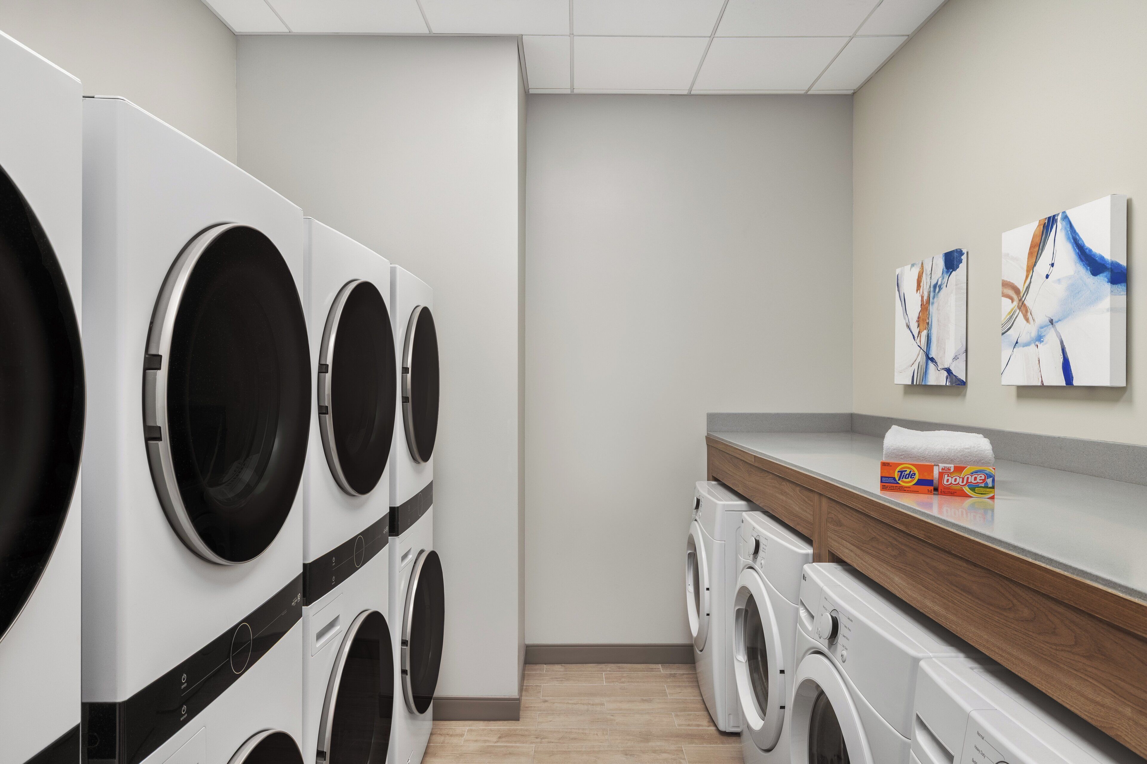 Un cuarto de lavandería con varias lavadoras, una encimera de madera y decoración mural abstracta.
