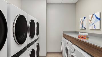 Un cuarto de lavandería con varias lavadoras, una encimera de madera y decoración mural abstracta.