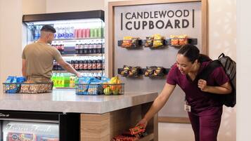 A self-service beverage station with a refrigerated drink display and a variety of snacks and packaged foods.