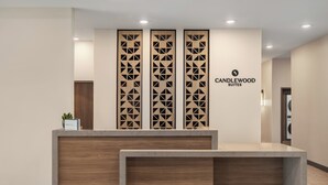 Un comptoir d’accueil au design moderne, le logo de Candlewood Suites et un panneau décoratif orné de motifs géométriques.
