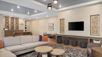 A modern living room with a sofa, round coffee tables, a flat-screen TV, and a fireplace.