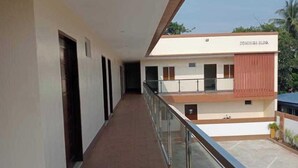 A long corridor with a glass railing, leading to a building with a sign reading "ESMIRICA BLD." - OYO 1122 Ranchotel Aklan (Kalibo)