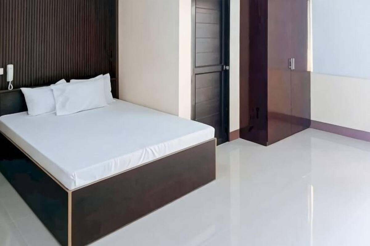 A modern bedroom with a large bed, a wooden headboard, and a door with a handle.
