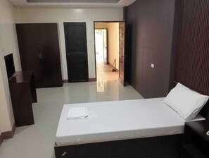 A bedroom with a bed, a desk, and two doors.