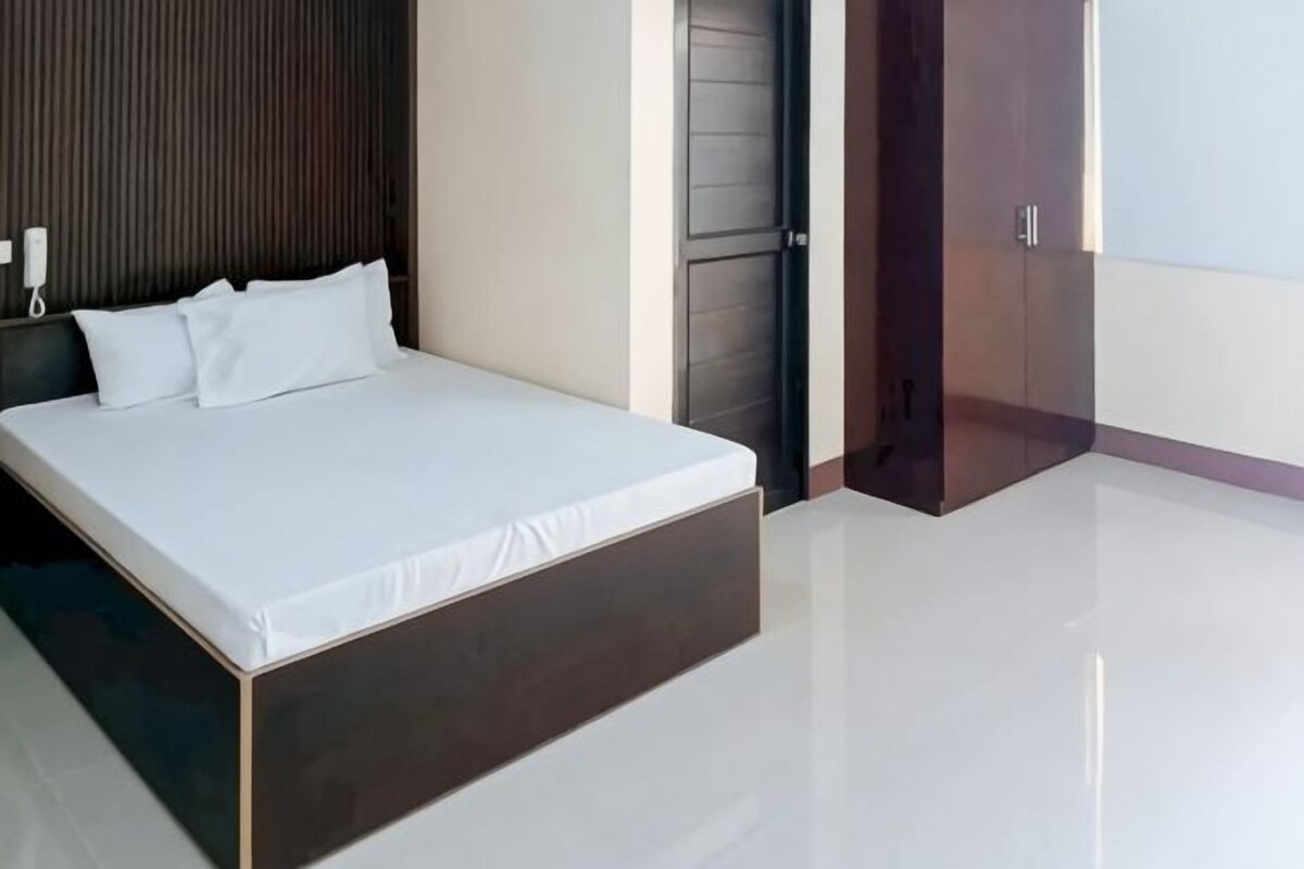 A modern bedroom with a large bed, a wooden headboard, and a door with a handle.