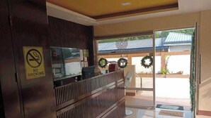 A reception area with a 'No Smoking' sign, a reception desk, and a view of the outside through a glass door. - OYO 1122 Ranchotel Aklan (Kalibo)