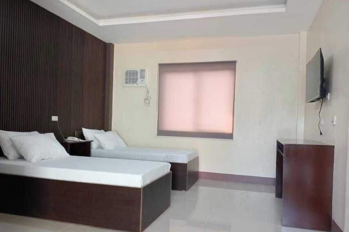 A hotel room with two beds, a TV, and a small desk.