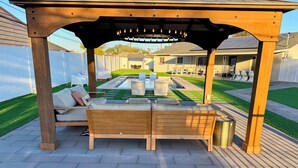 A wooden pergola with a seating area and a small pool.