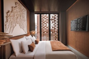A hotel room with a bed, pillows, a wall-mounted TV, and a decorative piece. - Earth Villa Canggu by Ini Vie Hospitality (Canggu)