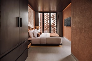 Un dormitorio moderno con cama, armario y vistas a través de una puerta celosía.