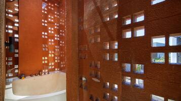 Un baño moderno con bañera, zona de ducha y una pared con pequeñas ventanas cuadradas.