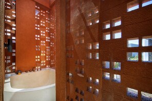 A modern bathroom with a bathtub, a shower area, and a wall with small square windows. - Earth Villa Canggu by Ini Vie Hospitality (Canggu)