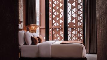 Una cama bien hecha con almohadas, una lámpara de noche y un cabecero de madera.