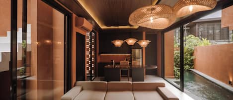 A modern interior with a seating area, a dining space, and a view of a water feature.