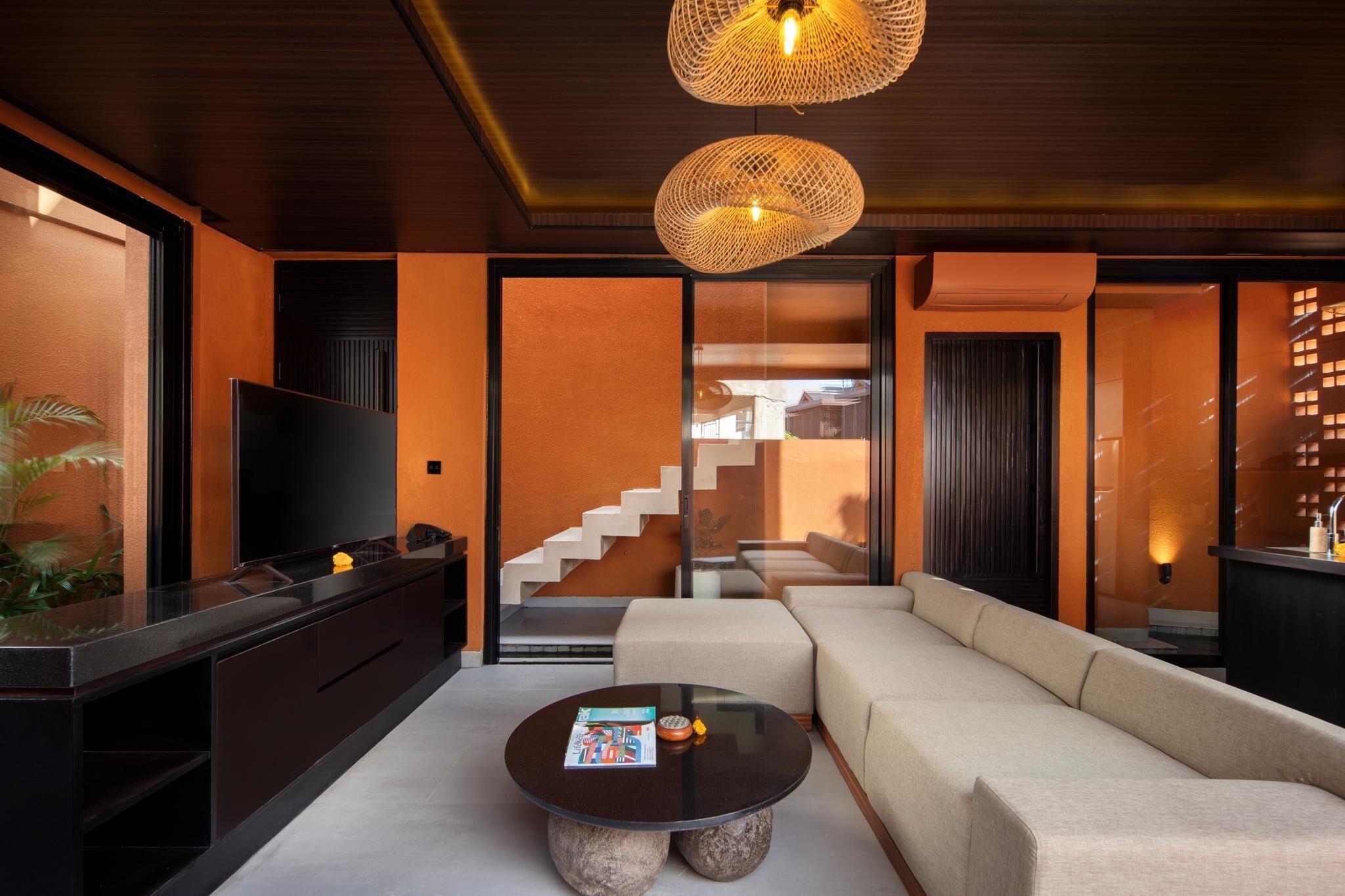 Una sala de estar moderna con un sofá, una mesa de centro, un televisor y una escalera que conduce a otro nivel.